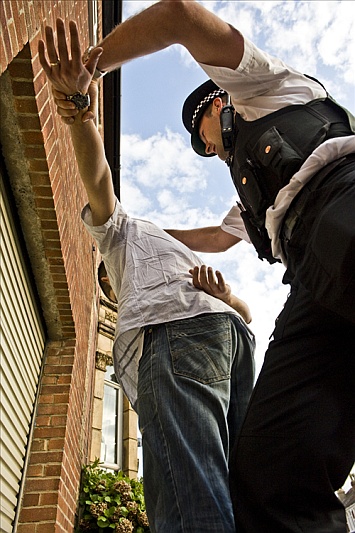 A policeman detains a suspect in the street.